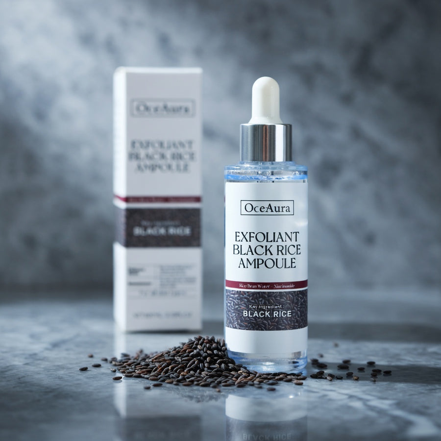 OceAura Exfoliant Black Rice Ampoule bottle and packaging on a gray surface with black rice seeds.